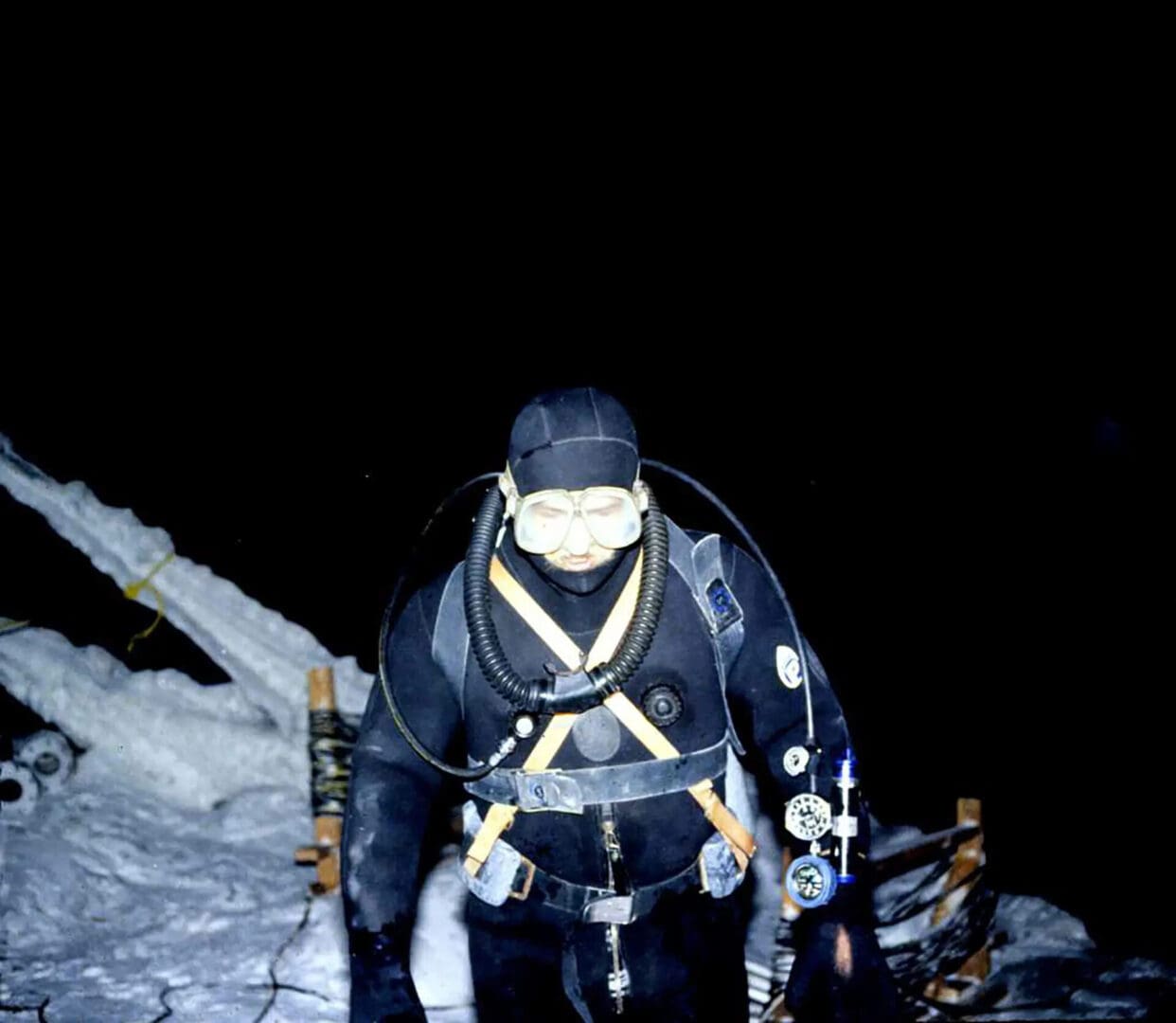 A man in black scuba gear standing on top of a mountain.