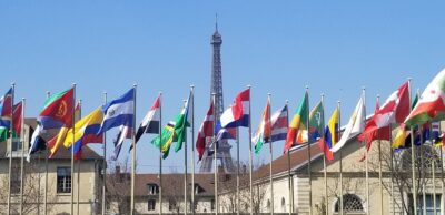 Multiple international flags with the Eiffel Tower in the background.